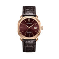 A rose gold watch with a burgundy dial and a leather strap, showing time and date.