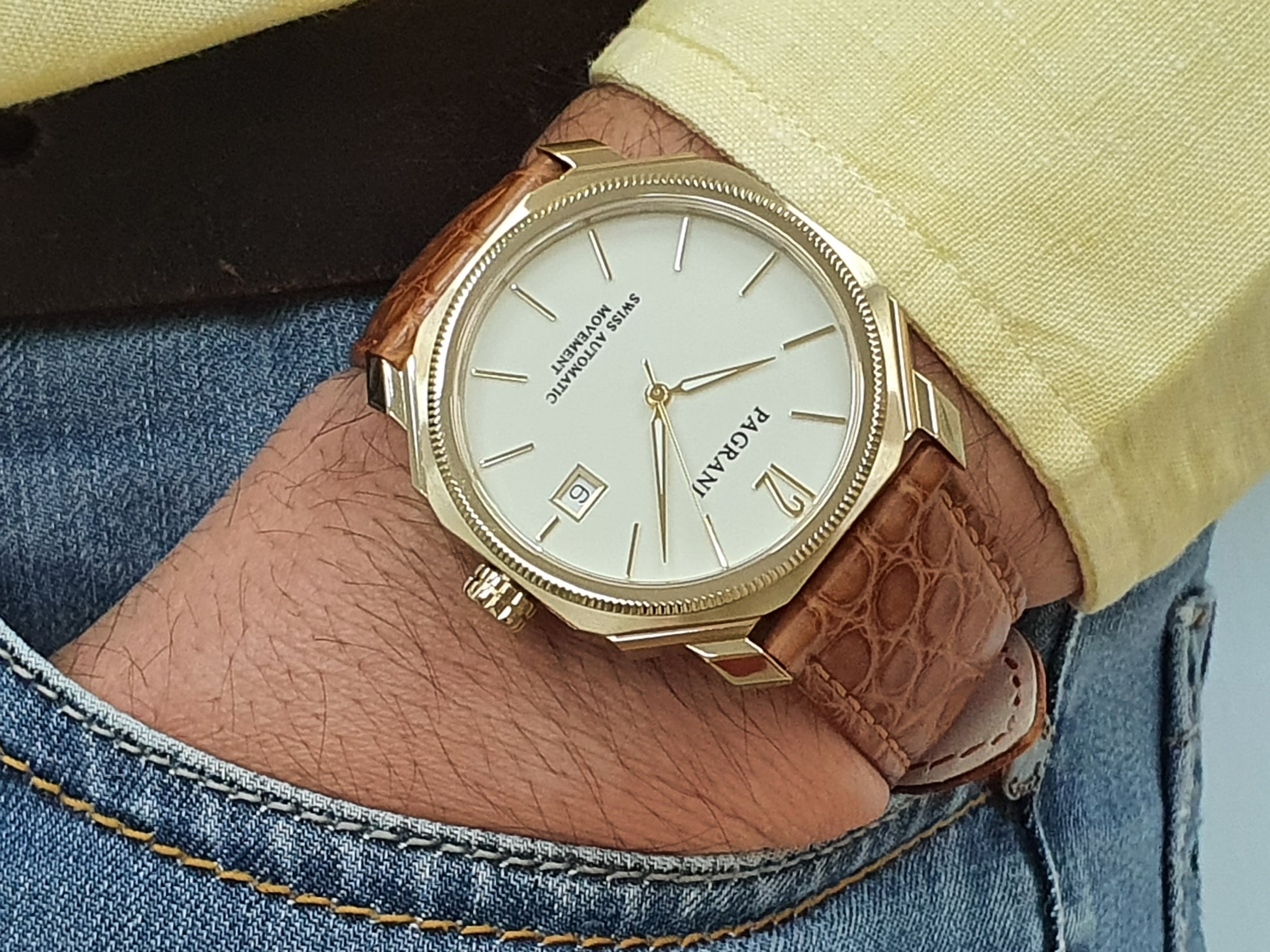 A gold-colored ultra-thin automatic date watch with a brown leather band and a white dial, displayed against a plain background.