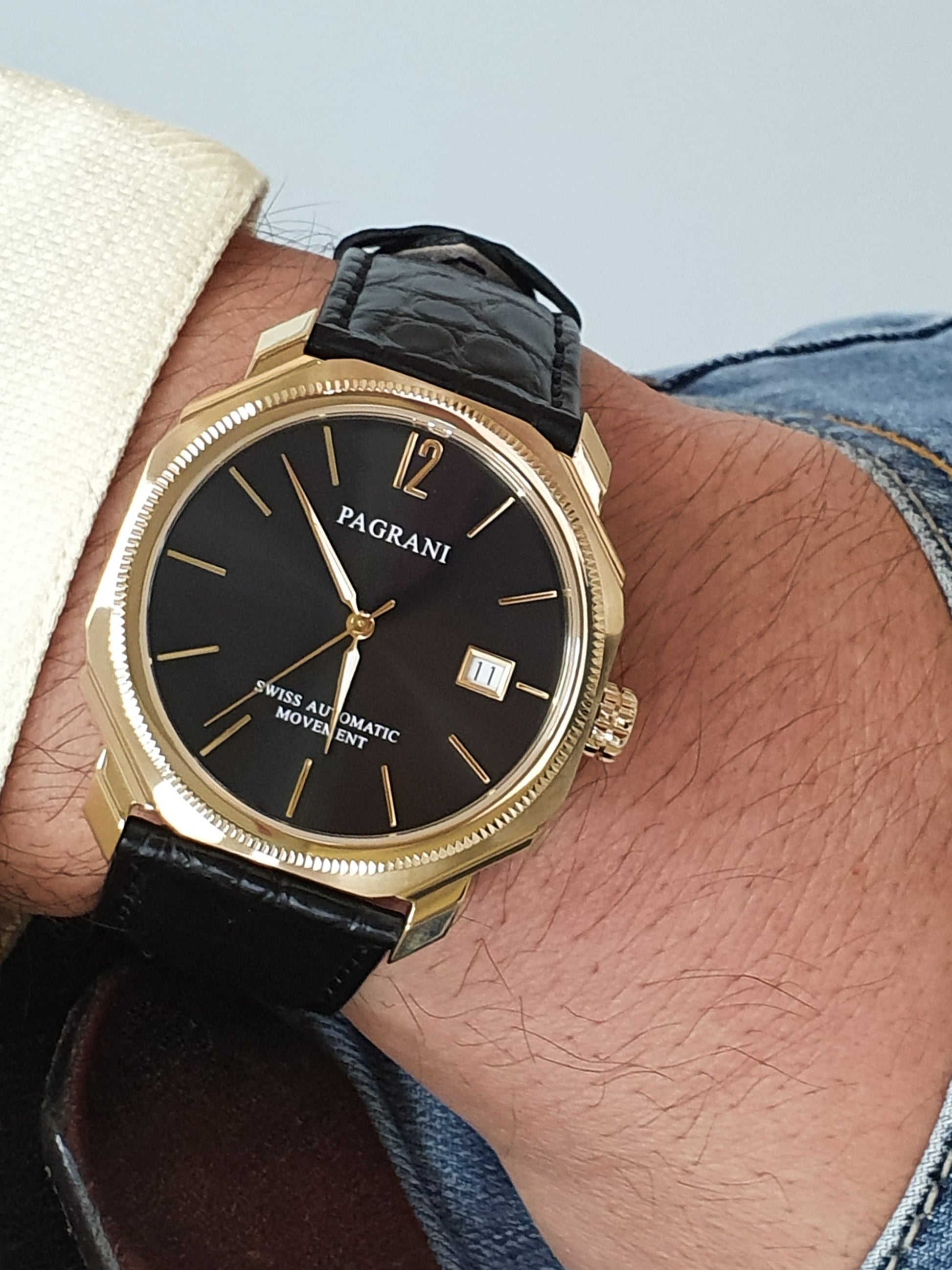 A gold-colored ultra-thin automatic date watch with a black leather band and a black dial featuring gold accents and the brand name 'PAGRANÉ' on the 12 o'clock position.