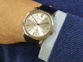 A silver-colored Pagran automatic date watch with a black leather band and a digital date display.